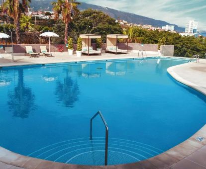 Terraza solarium con mobiliario, piscina y vistas de este hotel solo para adultos.