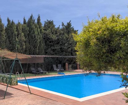 Zona exterior con piscina y solarium rodeada de vegetación de este tranquilo hotel rural.