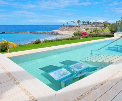 Hermosa piscina con tumbonas en el agua y vistas al mar de este hotel solo para adultos.