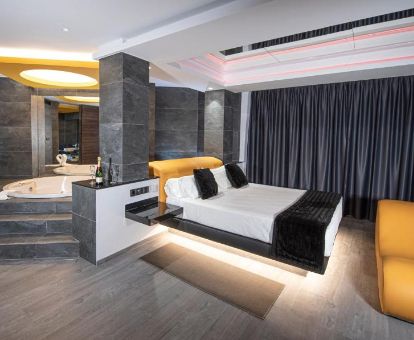 Elegante suite con bañera de hidromasaje privada junto a la cama de este hotel solo para adultos.