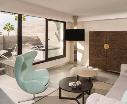 Luminosa sala de estar y terraza con jacuzzi privado de la suite premium del hotel.
