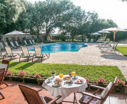 Amplia zona exterior con jardines, piscina al aire libre y zona de desayunos de este acogedor hotel rural.