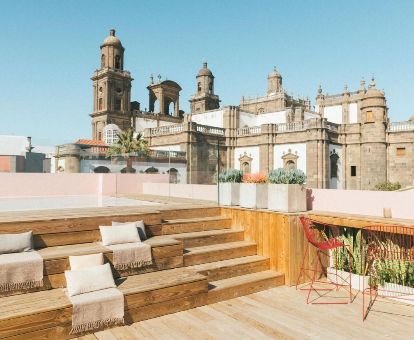 Terraza solarium con mobiliario y piscina con vistas a la catedral de Santa Ana de este hotel solo para adultos.