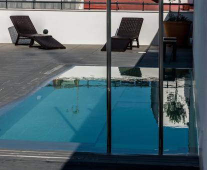 Foto de la piscina con fondo de cristal y solarium del hotel.