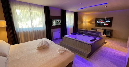 Jacuzzi rectangular para dos personas junto a la cama y con la televisión a un lado en la suite del Felix Hotel