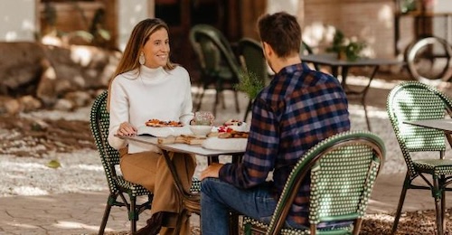 Una pareja desayunando en una mesa del exterior sentados en sillas bajo los árboles en Hotel Villa Retiro