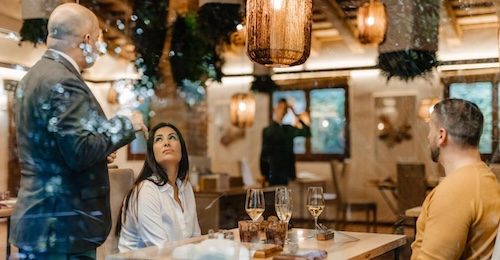 Pareja tomando una copa de vino blanco y hablando con el camarero en un restaurante elegante y con decoración romántica en Hotel Villa Retiro
