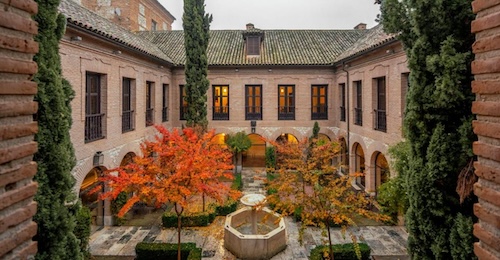 Foto del patio exterior con jardines y suelo empedrado con una fuente en el centro del Parador de Chichón cerca de Madrid