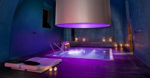 Foto de la piscina interior con tratamiento de hidromasaje y dos tumbonas en el suelo del Hotel Parador Alcalá de Henares