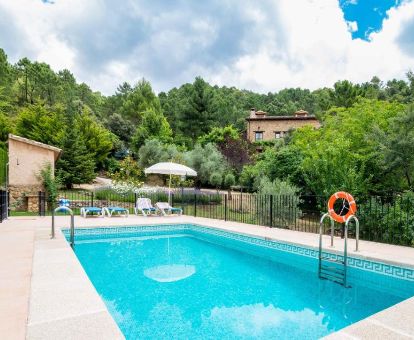 Zona exterior con piscina al aire libre rodeada de vegetación, en este acogedor hotel rural.